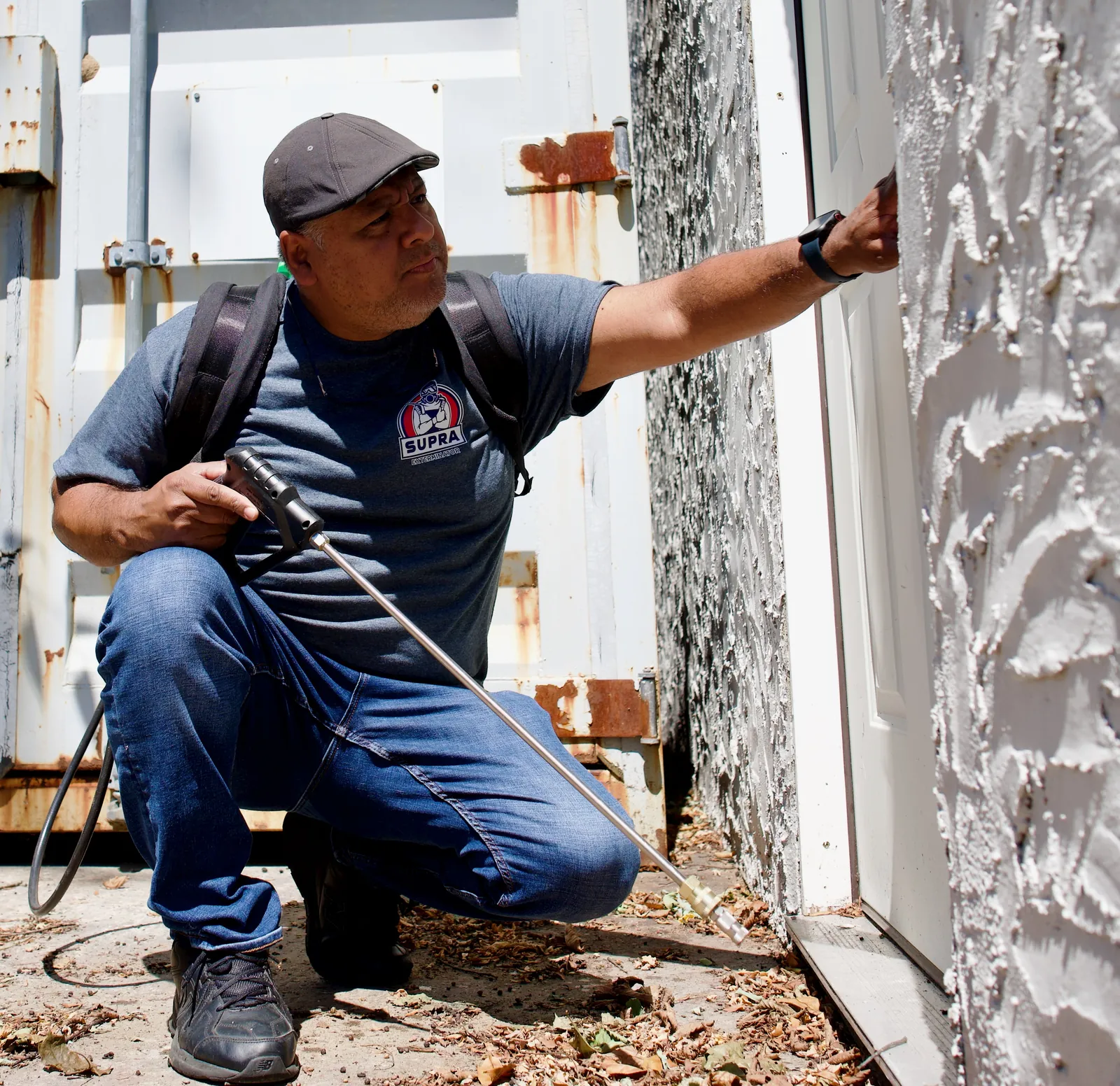 Supra Exterminator owner inspecting an exterior wall for pest entry points on Long Island
