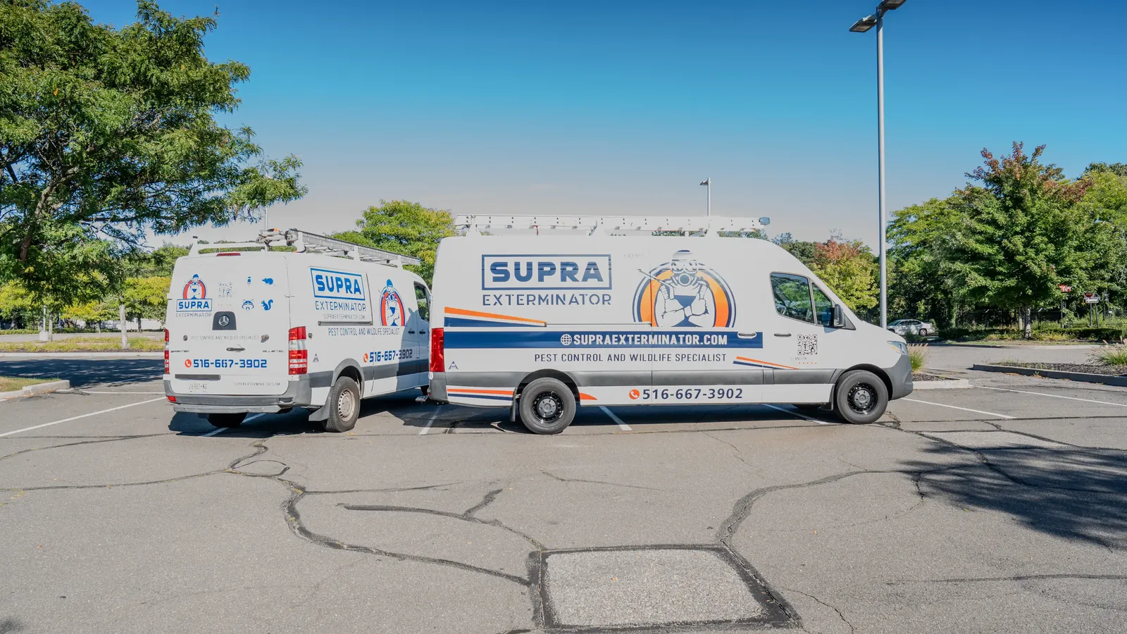 Two marked Supra Exterminator service vans labeled pest control and wildlife specialist